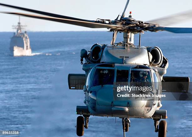 atlantic ocean, march 16, 2006 - an mh-60s seahawk helps conduct a vertical replenishment, while the guided-missile cruiser uss leyte gulf (cg-55) commences her approach prior to conducting a connected replenishment. - cruzador navio de guerra - fotografias e filmes do acervo