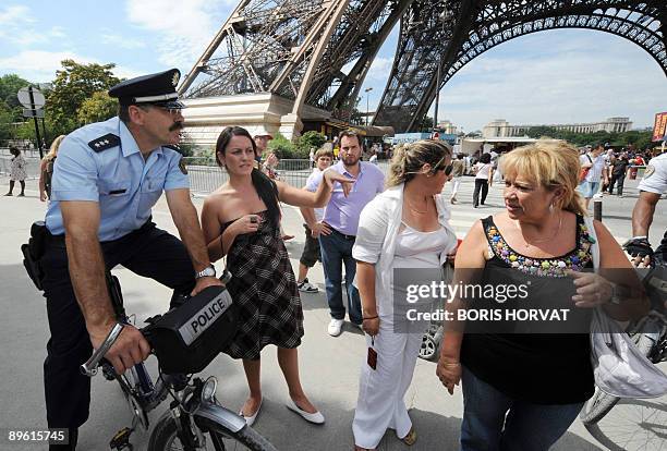 German policeman Martin Decker speaks to tourists on his bike in front of the Eiffel Tower in Paris on August 5, 2009. Decker is one of eight...