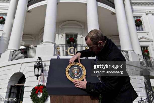 White House staff member adjusts the presidential seal before a tax bill passage event with U.S. President Donald Trump, not pictured, and Republican...