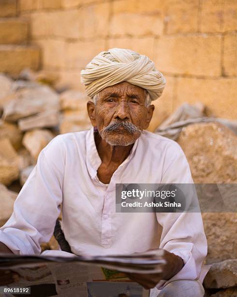 portrait of man in a turban holding a newspaper - pensive indian man stock pictures, royalty-free photos & images