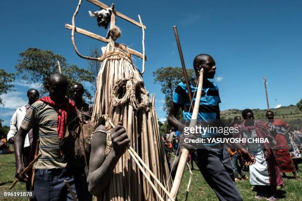 Circumcised Maasai young men wearing a ritual costume covered with hunted birds, come out from the bush to receive blessing from ceremony masters...