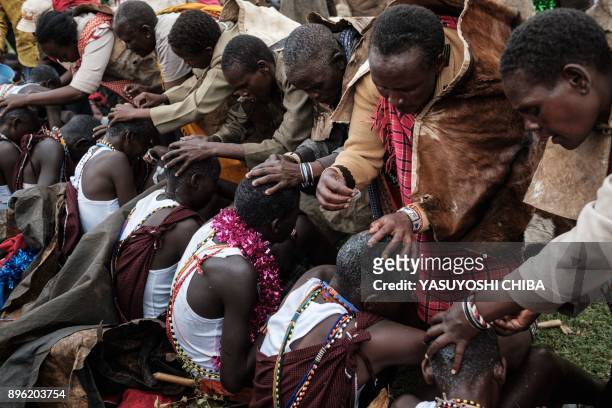 The hair of circumcised Maasai young men are shaved by their mother after coming out from the bush near Kilgoris, Kenya, on the last day of the...