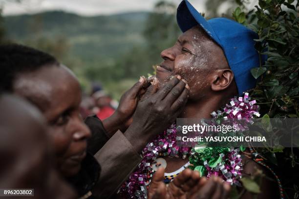 Circumcised Maasai young man reacts as her mother puts milk butter on his face after he came out from the bush near Kilgoris, Kenya, on the last day...