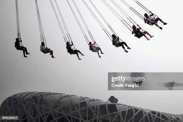 Tourists swing at an amusement park near the National Olympic Stadium, known as Bird's Nest on August 4, 2009 in Beijing, China. The Olympic Green...