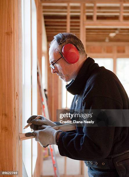 construction worker measuring wood at construction - dana workman stock pictures, royalty-free photos & images