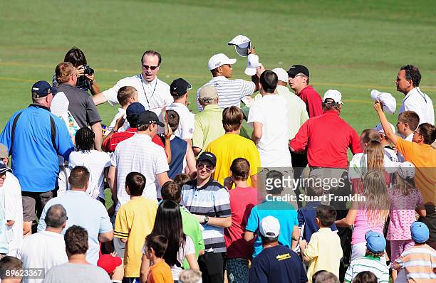 Tiger Woods of the U.S. Throws a hat as he is chased by young fans during a practice round of the World Golf Championship Bridgestone Invitational on...