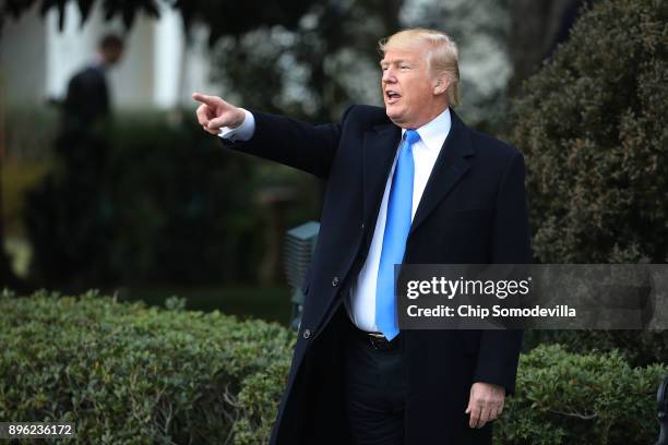 President Donald Trump points to guests at the conclusion of an event to celebrate Congress passing the Tax Cuts and Jobs Act on the South Lawn of...