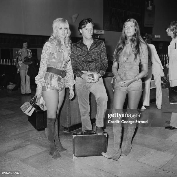 American businessman Hugh Hefner with Playboy's playmates Rosamund Teller and Marilyn Cole at Heathrow Airport, London, UK, 11th August 1971.