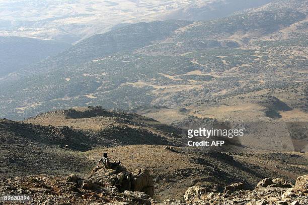 Lebanese Christian pilgrim sits on a cliff upon his arrival with others at a grouping area on August 5, 2009 before climbing to the top of Mount...