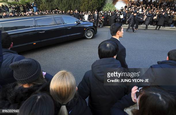 The hearse carrying the body of late SHINee singer Kim Jong-Hyun leaves as fans watch at a hospital in Seoul on December 21, 2017. Kim, a 27-year-old...