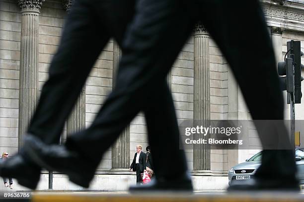 Businessmen walk past the Bank of England in London, U.K., on Thursday, July 9, 2009. The Bank of England stuck to its plan to buy bonds with 125...