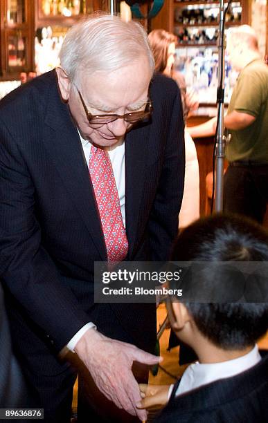 Warren Buffett, chairman of Berkshire Hathaway Inc., shakes the hand of Ziyang Danyang, son of Zhao Danyang, director of Pureheart Asset Management,...