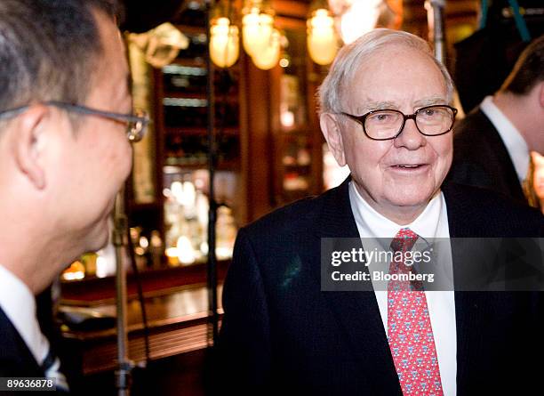 Zhao Danyang, director of Pureheart Asset Management, left, looks towards Warren Buffett, chairman of Berkshire Hathaway Inc., at Smith & Wollensky...