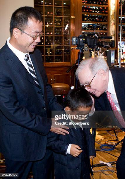 Warren Buffett, chairman of Berkshire Hathaway Inc., right, whispers in the ear of Zhao Ziyang, son of Zhao Danyang, director of Pureheart Asset...