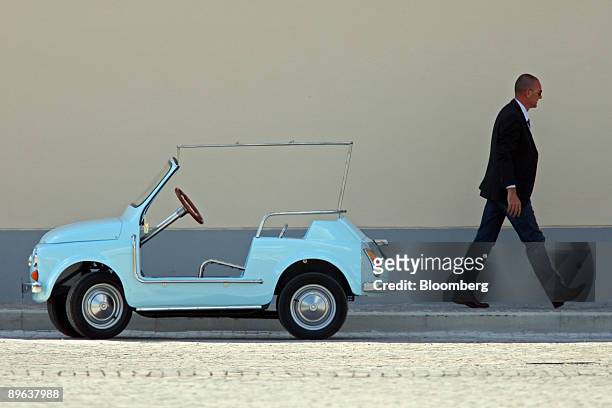 Security guard passes a modified electric Fiat 500 convertible automobile at the G8 summit in L' Aquila, Italy, on Thursday, July 9, 2009. Group of...