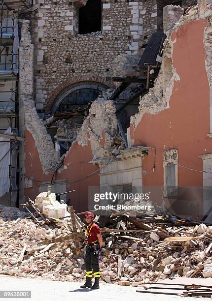 Rescue worker stands next to buildings damaged by the earthquake in L'Aquila, Italy, on Thursday, July 9, 2009. Group of Eight leaders said the...