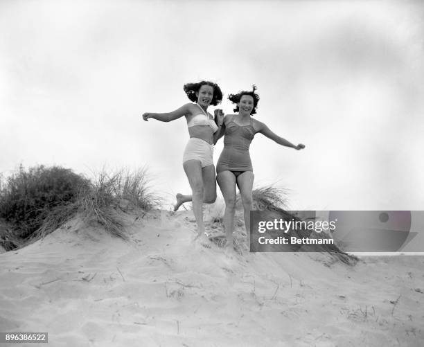 Florence Chadwick and her friend, Mrs. Scotty Van Dermeer are shown romping on the dunes at a resort near Cap Gris Nez.