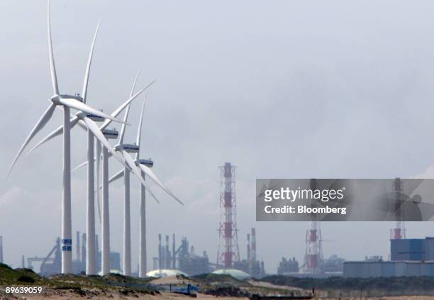 Wind turbines stand in front of smokestacks at the Hasaki Wind Farm in Kamisu City, Ibaraki Prefecture, Japan, on Tuesday, July 7, 2009. Prime...