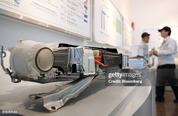 Employees work near a model of nickel-metal hydride batteries for Toyota Motor Corp.'s third-generation Prius hybrid vehicles manufactured by...