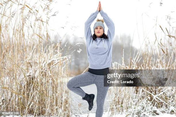 schöne brünette feminin sportlich frau praktizieren yoga im schnee - yoga in the snow stock-fotos und bilder