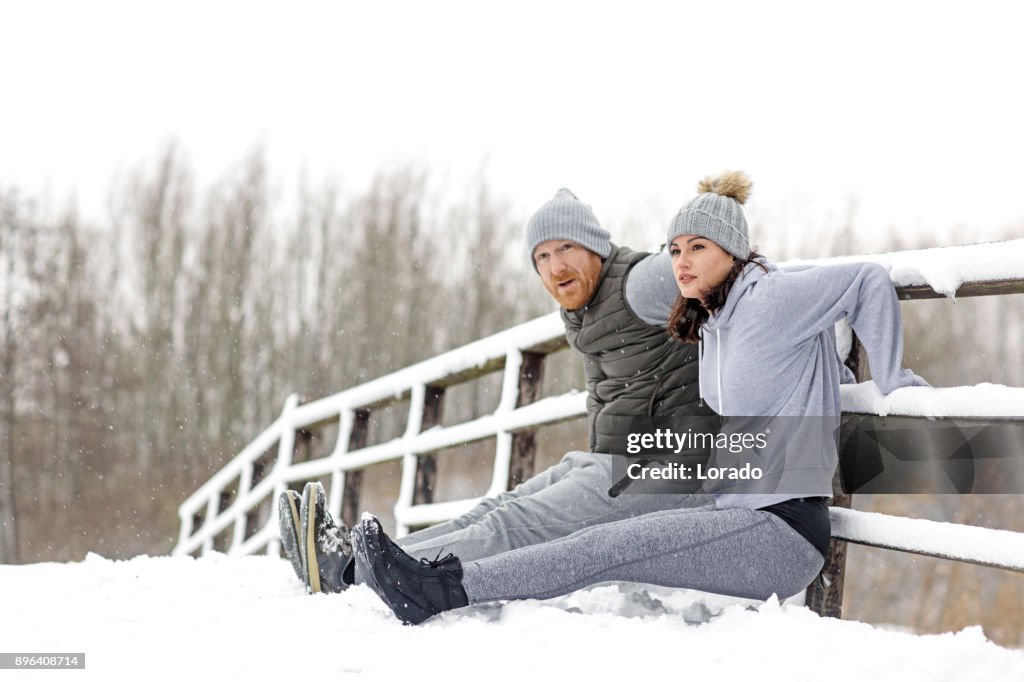 Beautiful Brunette Feminine Athletic Woman training outdoors with redhead personal trainer in the snowy countryside