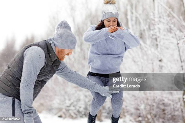 hermosa mujer atlética femenina morena entrenamiento al aire libre con entrenador personal pelirroja en el campo cubierto de nieve - sports training clinic fotografías e imágenes de stock