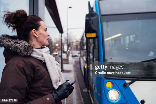 woman getting ready to step on bus cummuting in winter. - montreal people stock pictures, royalty-free photos & images