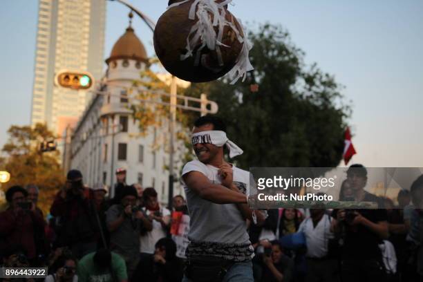 Demonstrators break a piñata with their eyes covered with a band written in Spanish with the word Indifference while marching to protest against the...