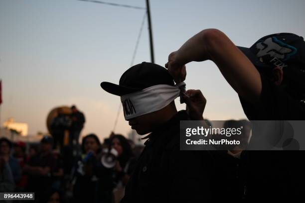 Demonstrators break a piñata with their eyes covered with a band written in Spanish with the word Indifference while marching to protest against the...