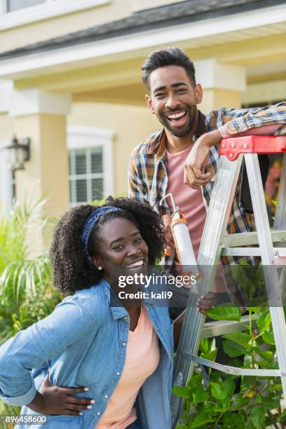couple doing home repairs outside house - caulk gun stock pictures, royalty-free photos & images