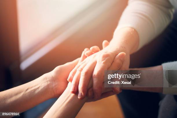 vieja y jóvenes  - hands clasped fotografías e imágenes de stock