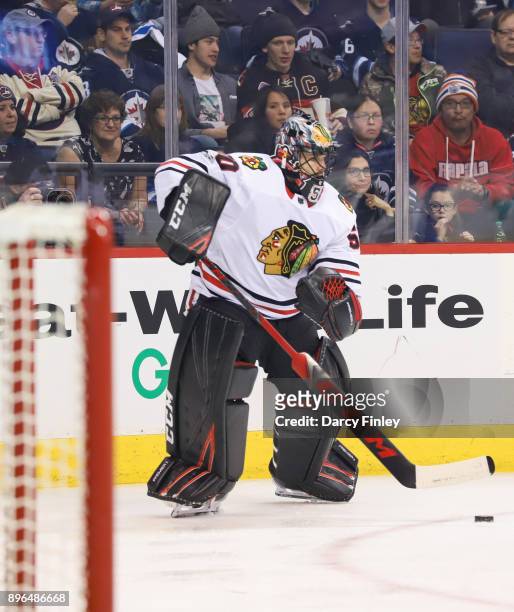 Goaltender Corey Crawford of the Chicago Blackhawks plays the puck along the boards during second period action against the Winnipeg Jets at the Bell...