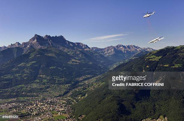 The new 90 foot high tech catamaran of the America's Cup defender Alinghi is seen airlifted with the Dents-du-Midi mountains over the Alps on August...