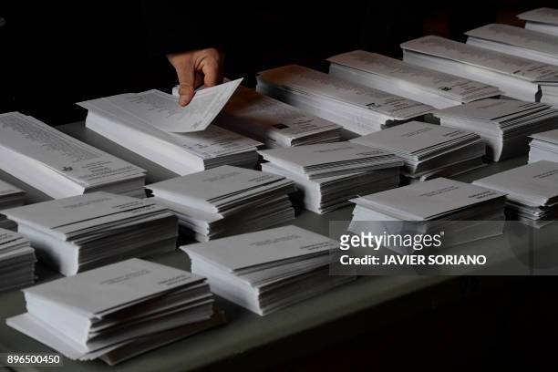 Man picks ballots before casting his vote for the Catalan regional election at a polling station in Barcelona on December 21, 2017. Catalans take...