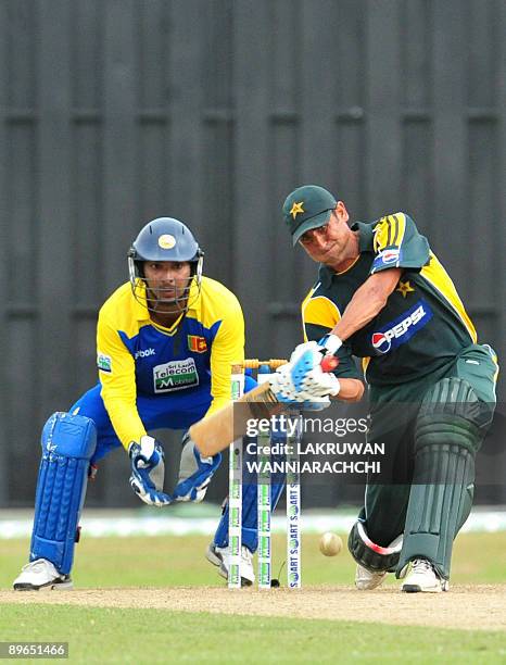 Pakistani cricket captain Younis Khan plays a shot as wicketkeeper Kumar Sangakkara looks on during the fourth One Day International match between...