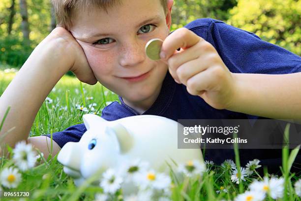 young boy putting money into piggy bank - kathy cash stock pictures, royalty-free photos & images