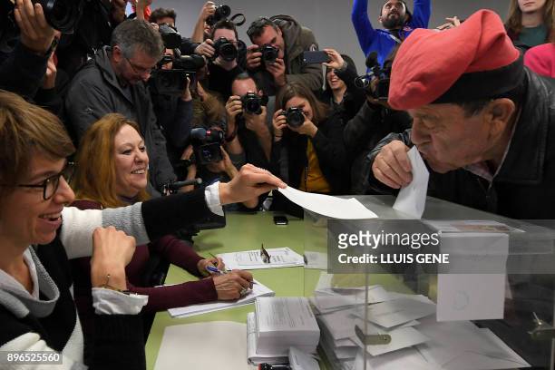 Man wearing an Catalan barretina hat kisses his ballot before casting his vote for the Catalan regional election at a polling station in Barcelona on...