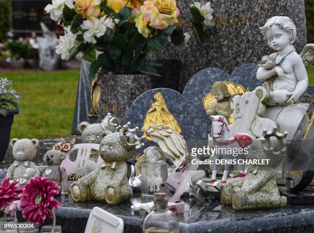 Photo taken on December 21, 2017 shows toys and figurines placed next to memorial stones on a grave at a cemetery in Lille. In Lille the association...