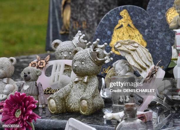 Photo taken on December 21, 2017 shows toys and figurines placed next to memorial stones on a grave at a cemetery in Lille. In Lille the association...