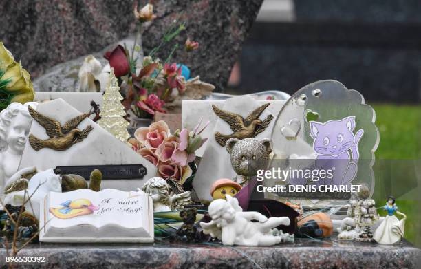 Photo taken on December 21, 2017 shows toys and figurines placed next to memorial stones on a grave at a cemetery in Lille. In Lille the association...