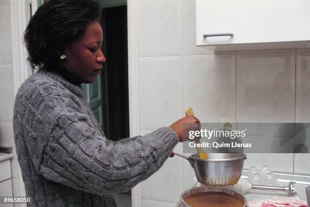 Guinean Inmigrant in Spain An guinean inmigrant cooks at her house. Alcala de Henares, Madrid province