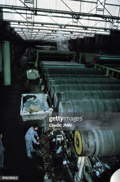 Uralita factory A man manages a machine that accommodates the uralita tubes in a factory. Alcazar de San Juan . Ciudad Real province
