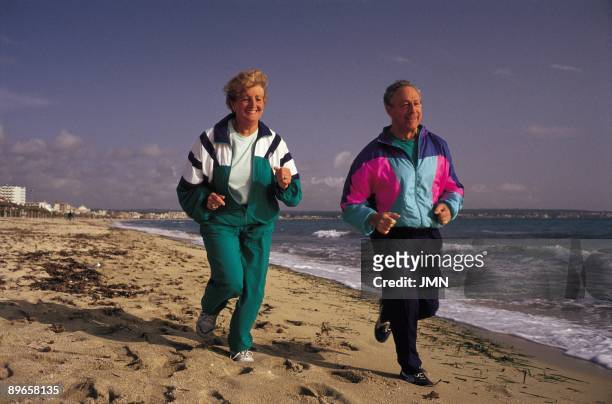 Aged couple running Aged couple doing footing on a beach