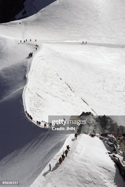 Route to the Mont Blanc `A group of mountaineer cover a distance between Aiguille du Midi and the Mont Blanc, France Alps