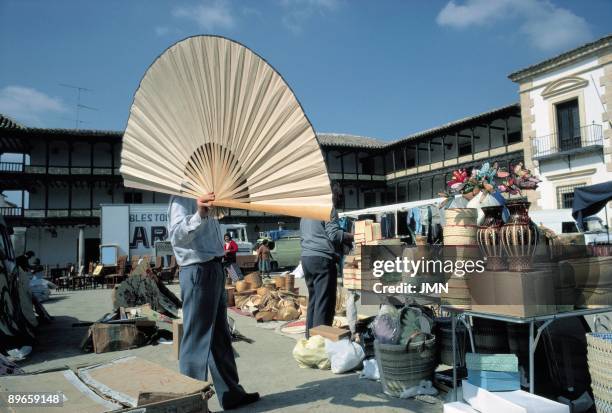Street market in Tembleque. Toledo A merchant shows a great fan in a street market installed in the Main Square