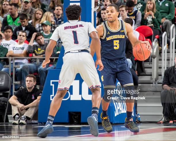 Jaaron Simmons of the Michigan Wolverines controls the ball in front of Jermaine Jackson Jr. #1 of the Detroit Titans during game one of the Hitachi...