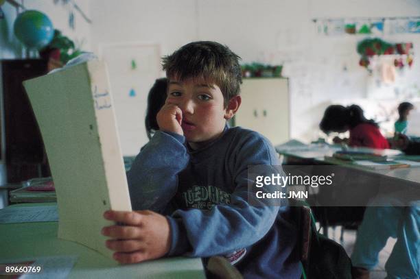 Seated boy in a classroom A boy poses with a text book in a classroom of a school of the Flores Island, Azores Islands