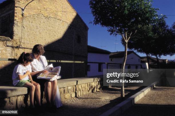 Girl reads with her teacher in the street A girl reads a text book with her teacher in the street of a village