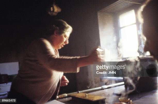 Woman prepares coffe A woman removes a coffeepot of the fire of her kitchen of coal and wood. Ancares Sierra, Lugo province