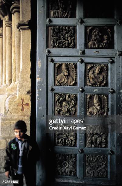 Door of the Romanic Church of Tui A boy is beside the maind door of the romanic Church of Tui. A Coruna province